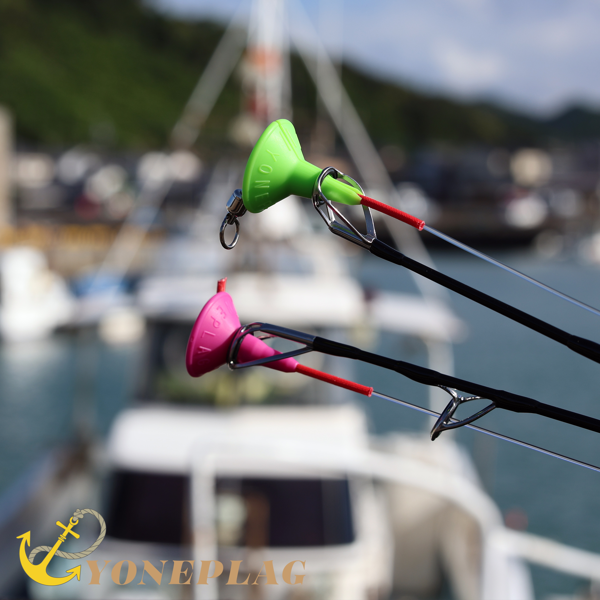 Two rods with YONEPLAG fitted to their top guides, harbor in the background